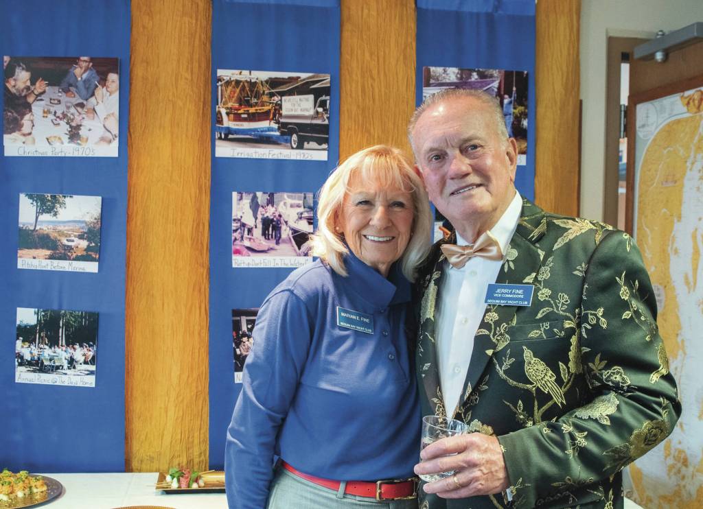 Photos by Emily Matthiessen
Marian and Jerry Fine, vice commodore of the Sequim Bay Yacht Club, pause before a display of images from the early days of the club during the 50th anniversary celebration at the John Wayne Marina.