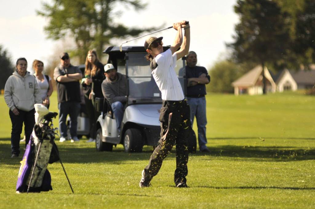 Sequim Gazette photo by Matthew Nash/
Cody Dunscomb shoots from the fairway with an audience behind him and teammate Adrian Aragon during an April 23 match with Kingston.