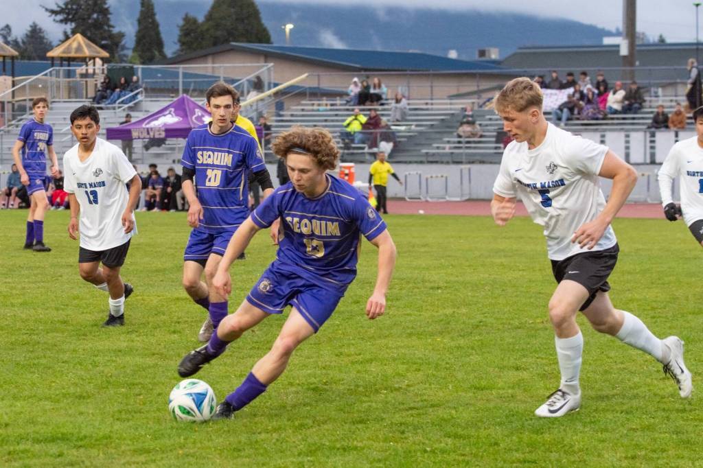 Photo by Emily Matthiessen/ Sequims Max Stanford drives past a North Mason player as teammate Colton Wagner looks on during the game on April 21 in Sequim.
