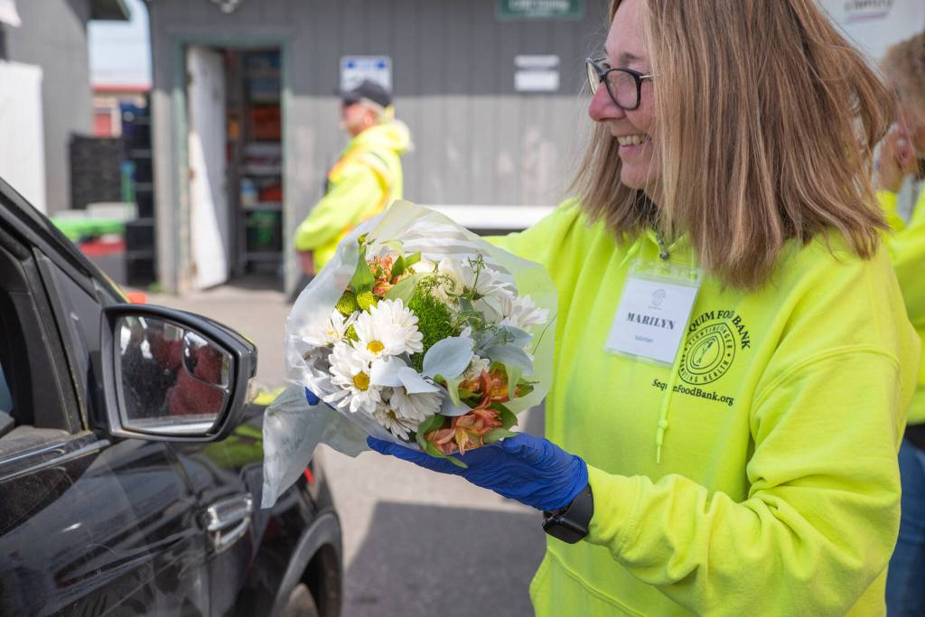 The communitys support of the Sequim Food Bank is evident in other ways besides donations of money and food. Here, volunteer Marilyn Pulk offers a bouquet of flowers donated by a local grocery store to a food bank client.