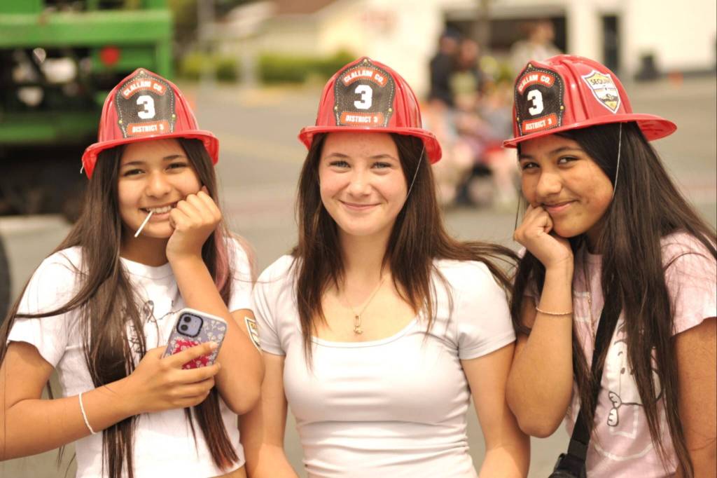 Sequim Gazette photo by Matthew Nash/
Friends Jordan Shay, Myah Neal, and Shanty Gallegos wear matching fire hats as they watch the Grand Parade.