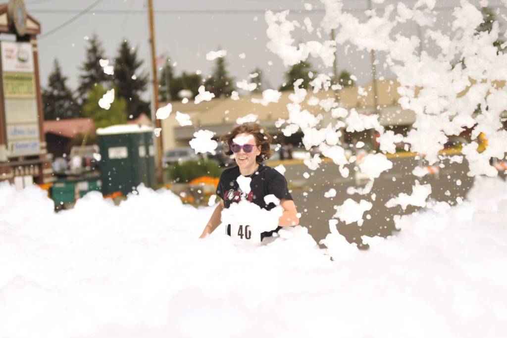 Sequim Gazette photo by Matthew Nash/
Molly Bishop of Sequim runs through foam courtesy Strait Up Foam Fun at the end of the Sequim Irrigation Festivals two mile Bubble Run on May 9. Bishop said it was her first time participating and that she practiced beforehand running to and from Carrie Blake Community Park and beat her personal best time.