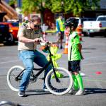 Sequim Gazette photo by Monica Berkseth/ Cub Scout Pack 4490 Assistant Scoutmaster Marcus Spooner assists his eight-year-old son Henry at Saturdays A Wheelie Good Day event celebrating National Bike Month.