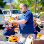 Sequim Gazette photo by Monica Berkseth/ Joseph MacDonald fits a helmet onto the head of his son George, 8, who participated in Saturdays city-sponsored biking event with his twin sister Evelyn.