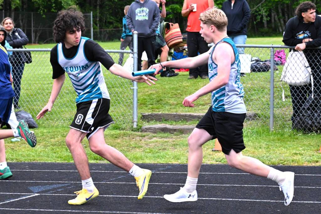 Nolan Oase takes the baton from Braylon Waters during the 4x400 meter relay. They and teammates Carter Fenner, and Will Brooks won first at the league meet running 4:25.87.