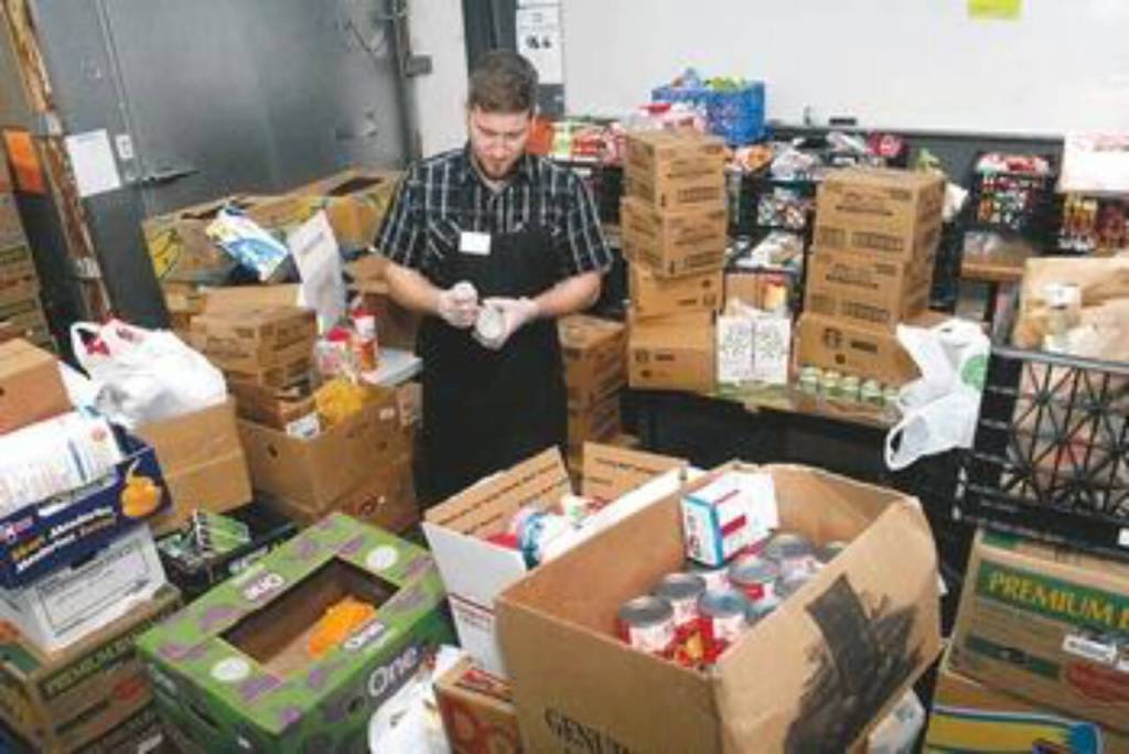 Peninsula News Group photo/ In this photo published in the Peninsula Daily News in 2015 or 2016, Perry, then the Port Angeles Food Banks warehouse manager, sorts food donations at the food banks former location at 401 S. Valley St.