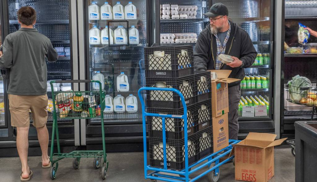 Sequim Gazette photos by Emily Mathiessen
A client shops at The Market at the Port Angeles Food Bank while Operations Manager Kevin Perry stocks the refrigerated cases.