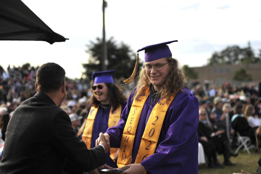 Dean Spaulding is all smiles after receiving his high school diploma from Sequim School Board director Michael Rocha.