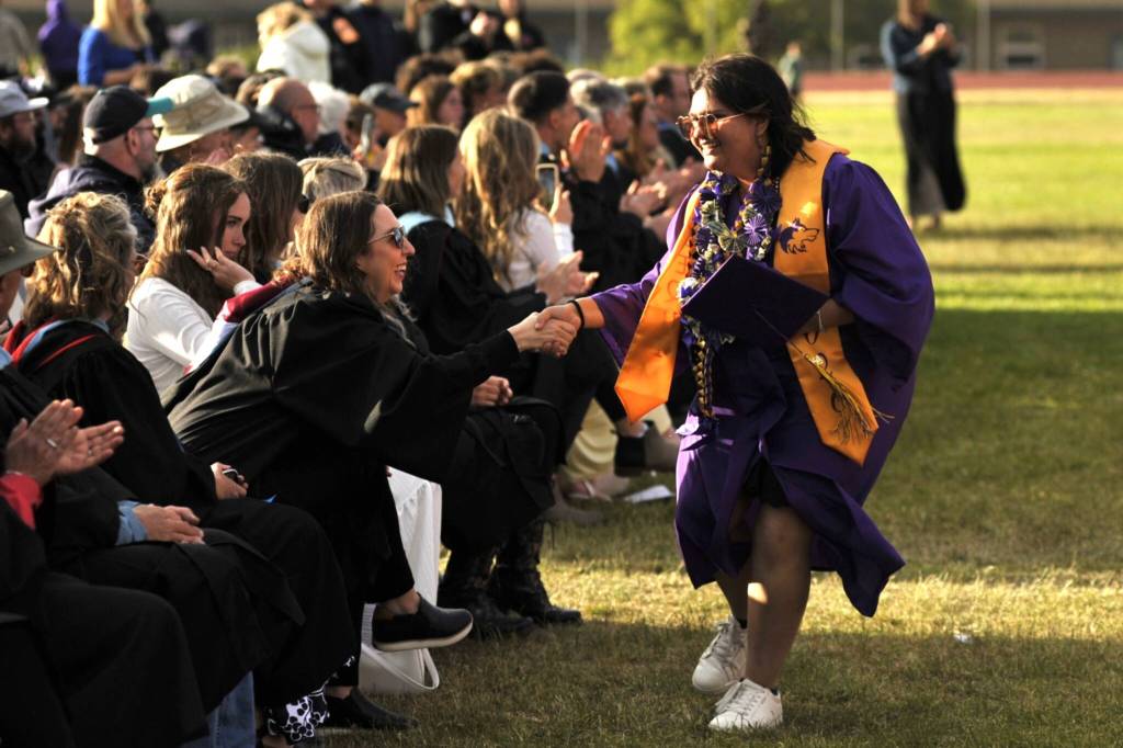 Sequim Gazette photo by Matthew Nash/ Sequim senior Anjaliden Wolfley shakes teacher Julie Rombergs hand as she walks down the front row to receive her diploma.