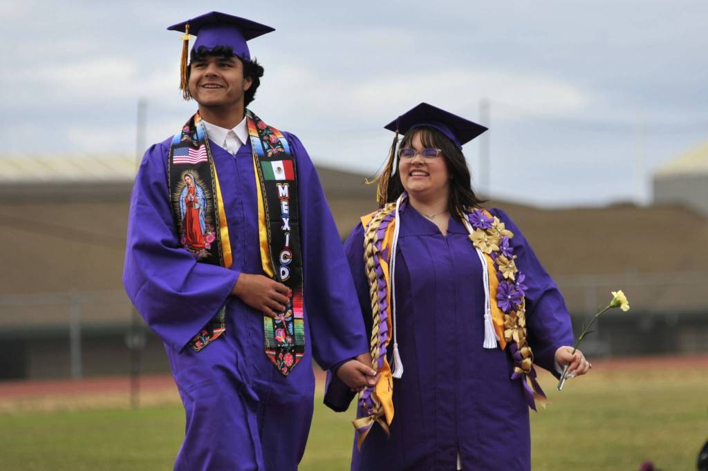 Sequim Gazette photo by Matthew Nash/ Abraham Herrera and Patience Leto spot family and friends in the stands as they walk to Sequim High Schools graduation ceremony on Friday night.