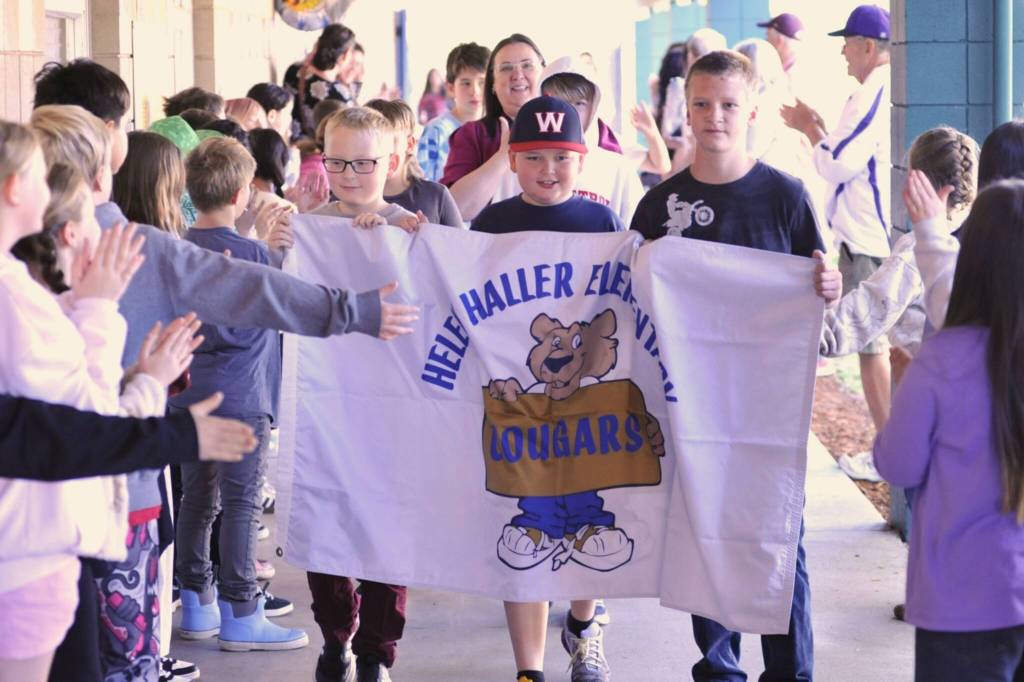 Fifth graders Oliver Nash, Bennett Castell and Levi Adolphe carry the banner for Helen Haller Elementary School as students and staff high-five fifth graders before their Moving On ceremony on June 11.