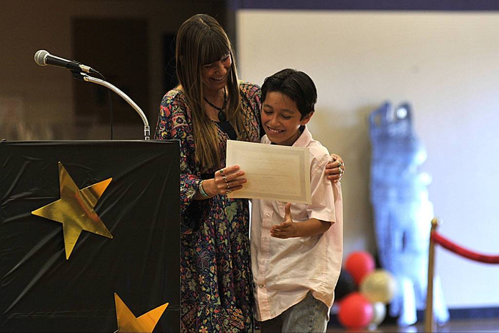 Sequim Gazette photo by Matthew Nash/ Fifth grade teacher Nathalie Maynock gives Luke Carroll his certificate celebrating fifth grade during a Moving On ceremony in Olympic Peninsula Academys gym.
