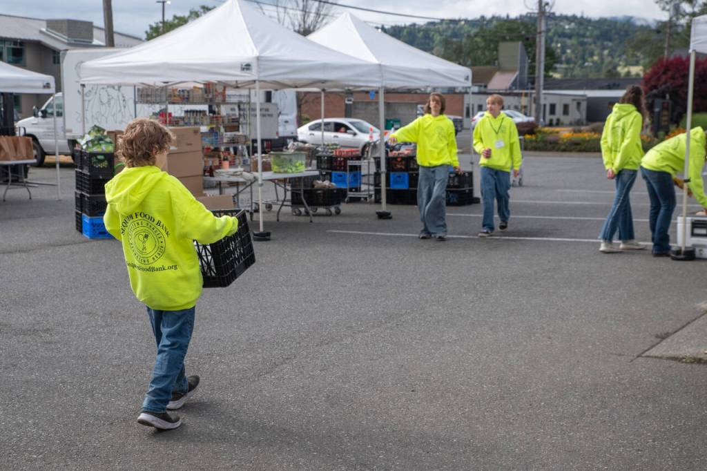 Sequim Gazette photos by Emily Matthiessen 
Kaysin Gluth, who recently turned 12, walks toward teen food bank volunteers CJ Furnish and Riley Gavin with a crate of food items to place at one of the outdoor food distribution stations. Gluth began volunteering at Sequims food bank at age 11.