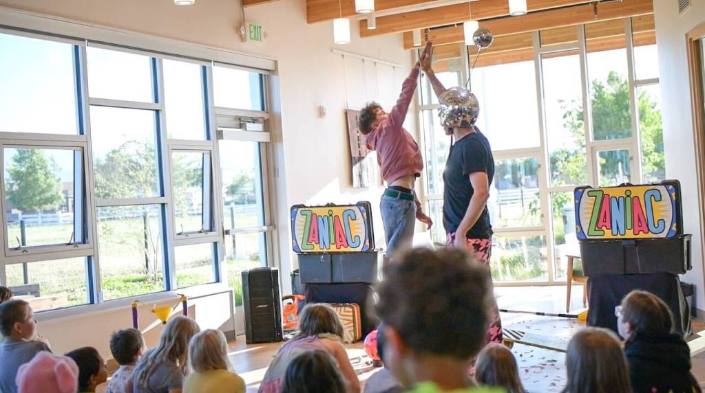 Sequim Gazette photo by Monica Berkseth/ Sawyer Hilliker gives The Zaniac a high-five after helping with a trick during an hour-long show at Sequim Branch Library on Tuesday, June 16.