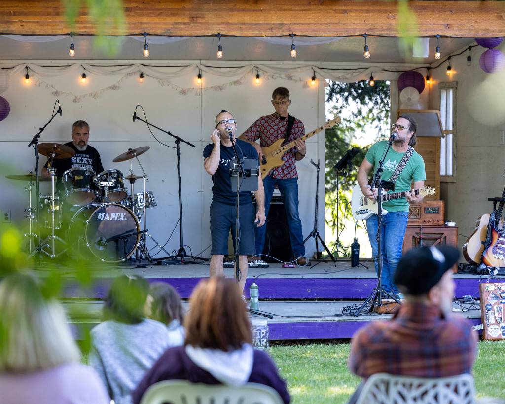 Sequim Gazette photo by Tom Buscher/ Members of Vibrations of Particles n Waves perform for visitors at Purple Haze Lavender Farm on July 18. Audience members watch from shaded seating as the band provides live music during the farms annual festival.