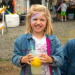 Sequim Gazette photo by Monica Berkseth/ Mabel Lepping. 4, of Sequim, is all smiles holding lemonade after getting her face painted for the first time at Frida Haas face painting studio during the Sequim Lavender Festival in the Park.