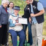 Sequim Gazette photo by Monica Berkseth/ Tom Sanford, executive director of North Olympic Land Trust, presents Janice Hunt, the youngest granddaughter of William Dick, who purchased the property and built the Big Red Barn Farm 1904, with the Farmer of the Year award on July 26.