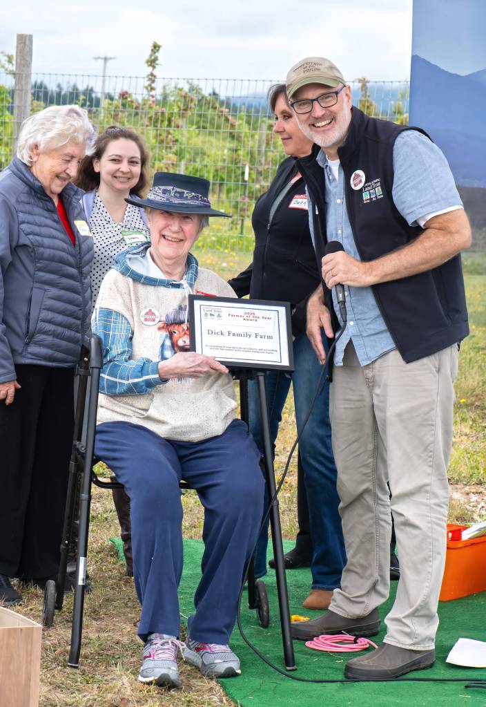 Sequim Gazette photo by Monica Berkseth/ Tom Sanford, executive director of North Olympic Land Trust, presents Janice Hunt, the youngest granddaughter of William Dick, who purchased the property and built the Big Red Barn Farm 1904, with the Farmer of the Year award on July 26.