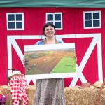 Sequim Gazette photo by Monica Berkseth/ Ayisha Jaffer, the North Olympic Land Trusts community relations director, holds a poster of the Big Red Barn Farms property that the trust looks to preserve as farmland forever.