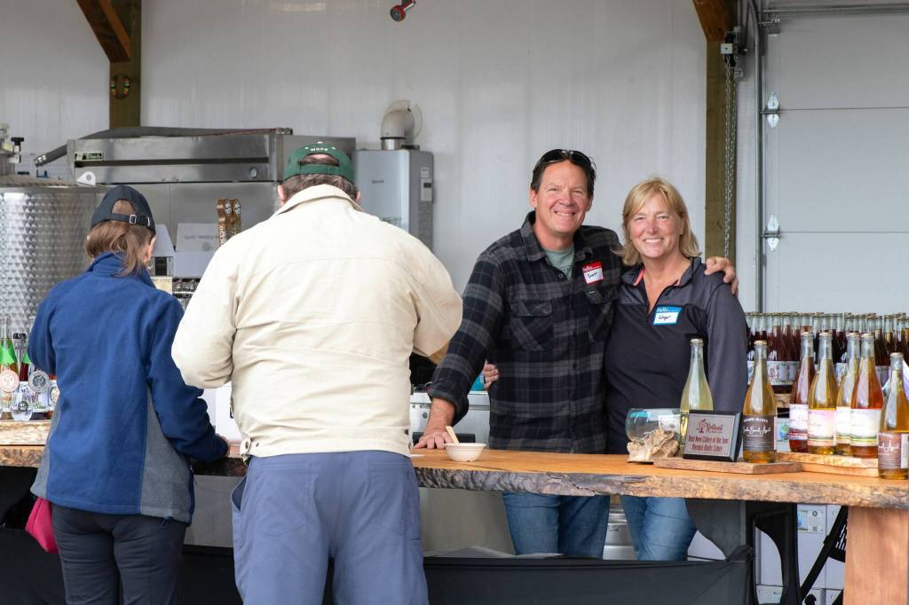 Sequim Gazette photo by Monica Berkseth/ Scott and Ginger Wierzbanowski, owners of the Olympic Bluffs Cidery and Lavender Farm, serve cider during the North Olympic Land Trusts Family Picnic on July 26. The couple has owned the property in Agnew for almost six years.