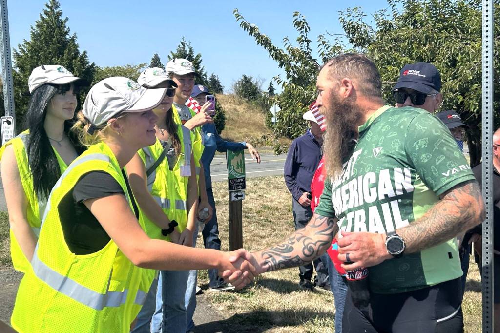 Sequim Gazette photo by Matthew Nash/ Patrick Smith of Florida greets Peninsula Trail Coalition trail ambassadors, including Ashton Reichner, on Aug. 3.