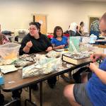 Family members, from left, Denise Helms, Amity Goodworth, Scarlett Goodworth and Thomas Goodworth look through stamps at the penny table during the Strait Stamp Show on Aug. 8. They got into stamp collecting following Amitys initial interest and now Scarlett is pursuing the hobby, too.