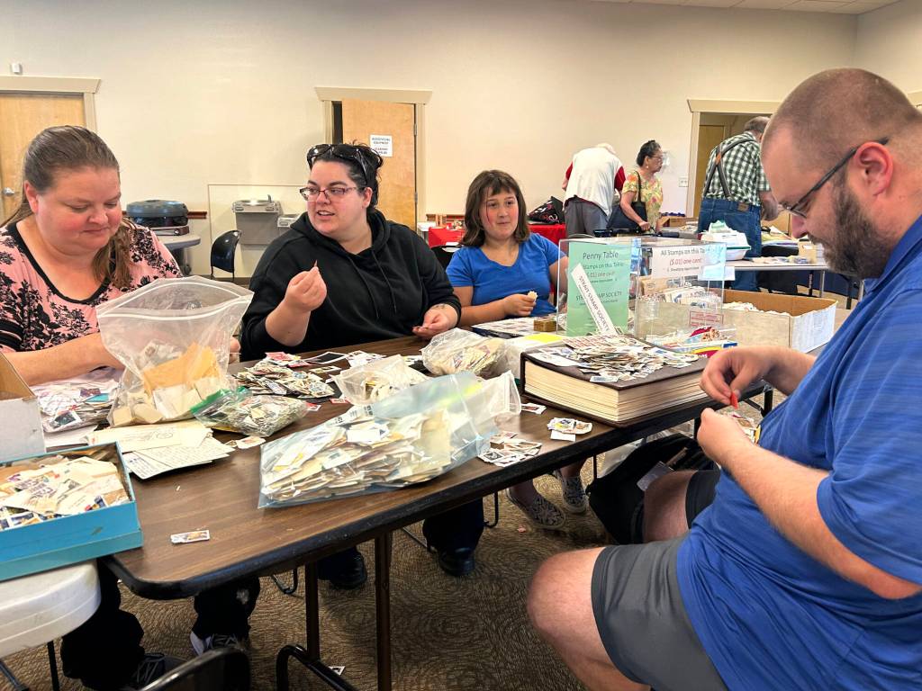 Family members, from left, Denise Helms, Amity Goodworth, Scarlett Goodworth and Thomas Goodworth look through stamps at the penny table during the Strait Stamp Show on Aug. 8. They got into stamp collecting following Amitys initial interest and now Scarlett is pursuing the hobby, too.