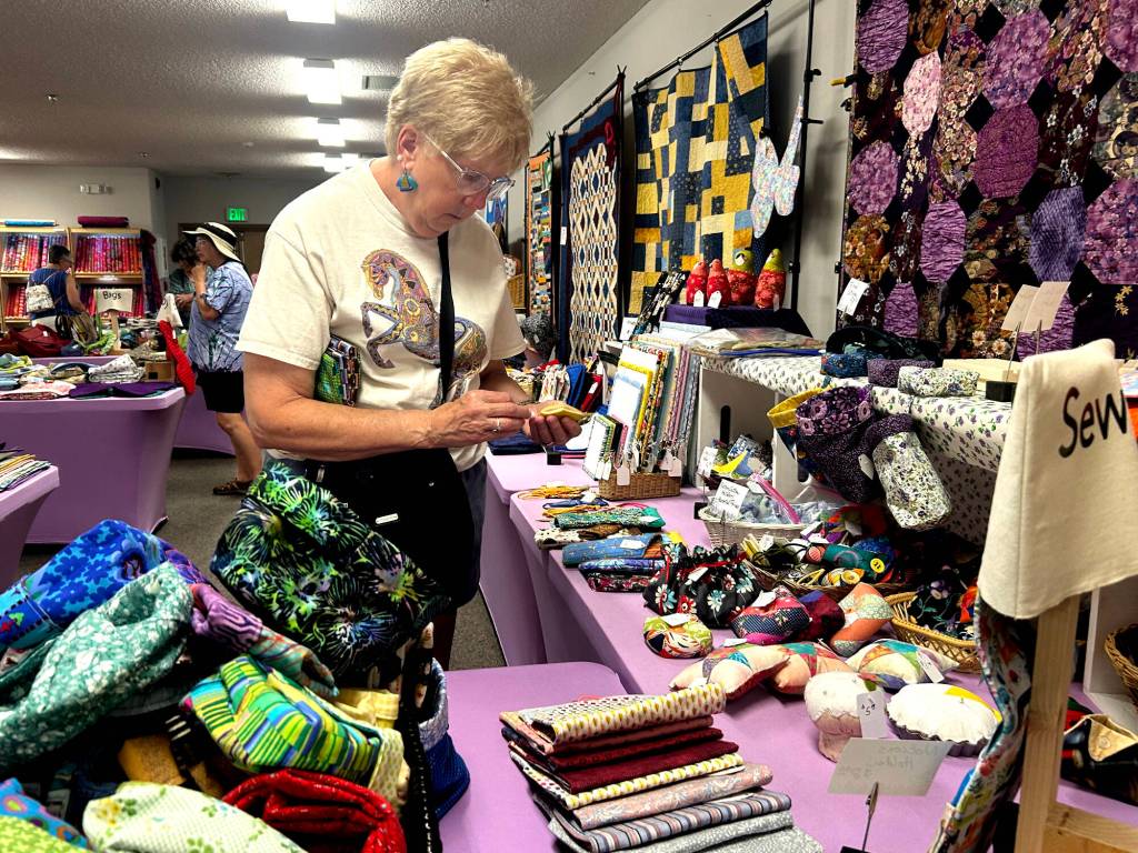 Sequim Gazette photo by Matthew Nash/ Teresa Frank of Sequim looks through items in the Quilters Boutique during the Sunbonnet Sue Quilt Clubs show. Frank, a national embroiderer judge, said she was devastated when the club didnt have their show last year. Folks here do such incredible work, she said.