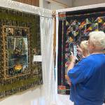 Sequim Gazette photo by Matthew Nash/ Greg Cherney with Kathy Pomeroy of California take a photo of the Sasquatch quilt by Rae Jean Dickinson. The couple said theyre particularly fond of Sasquatches.