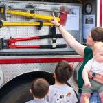 Sequim Gazette photo by Monica Berkseth/ Samantha Mangiameli points out firefighter tools to Luca and Finley while holding baby Leo during the Unity of Effort.