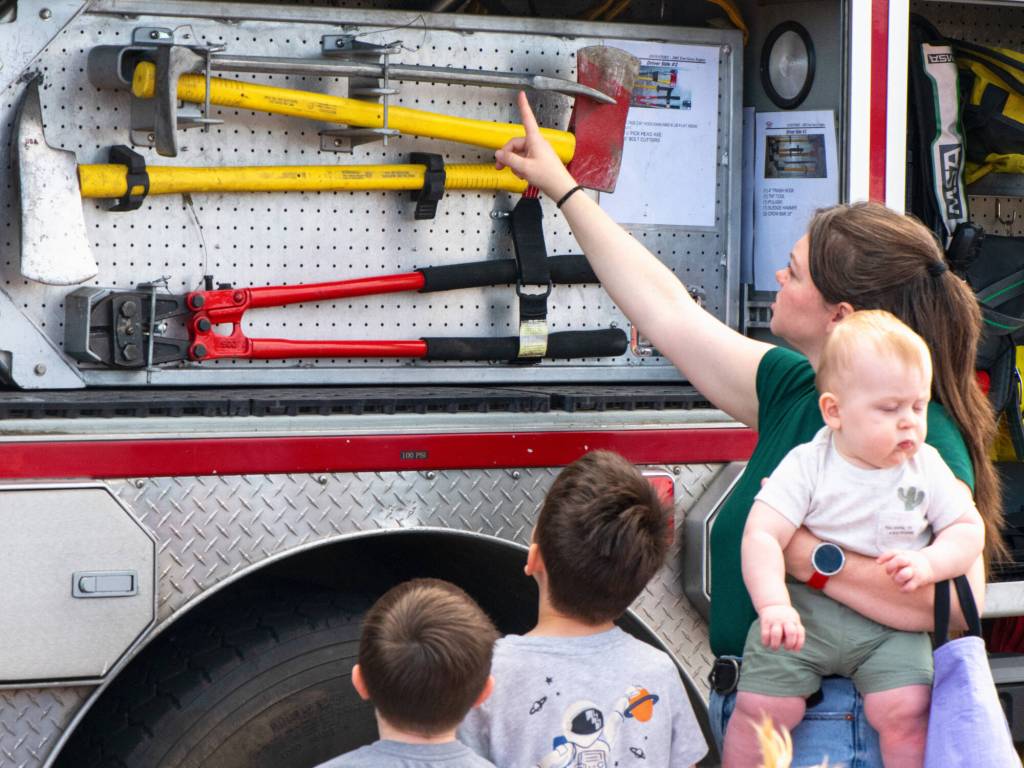 Sequim Gazette photo by Monica Berkseth/ Samantha Mangiameli points out firefighter tools to Luca and Finley while holding baby Leo during the Unity of Effort.
