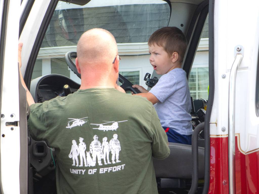 Sequim Gazette photo by Monica Berkseth/ Two-year-old Noah Pedde sits in a fire trucks drivers seat during Unity of Effort as his dad Brian of Snohomish watches.
